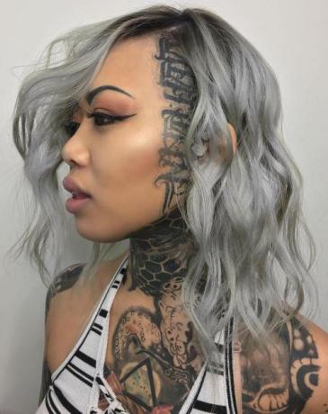 Stredne vlnitý sivý účes s tetovaním na hlave