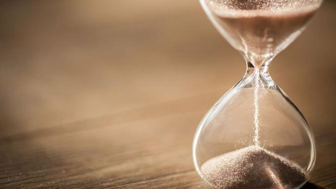 Sand som löper genom lamporna i ett timglas som mäter tiden