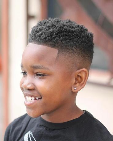 Un corte de pelo de desvanecimiento de piel alta con giros para niños negros pequeños