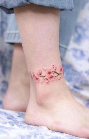 Tatuaggio alla caviglia con fiori di ciliegio