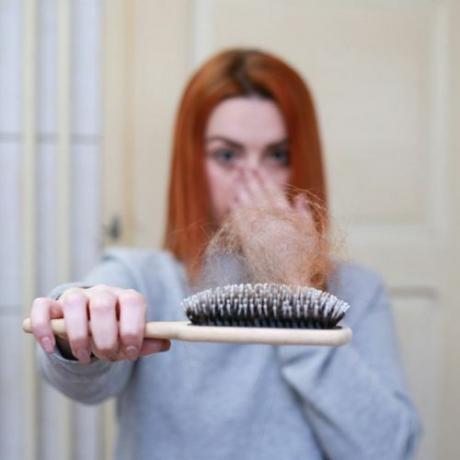 Mujer sosteniendo un cepillo con muchos pelos perdidos