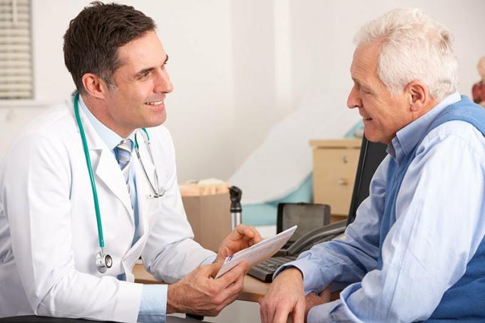Médico americano falando com um homem idoso em cirurgia