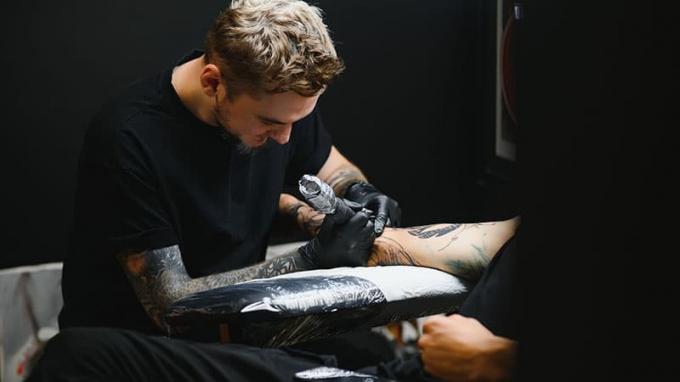 Professionele tatoeëerder werkt in zijn tattoo-studio.