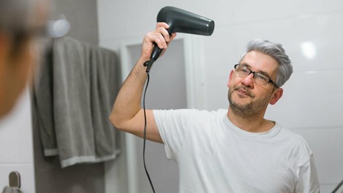 Stredoveký muž sušiaci vlasy v kúpeľni so sušičom vlasov