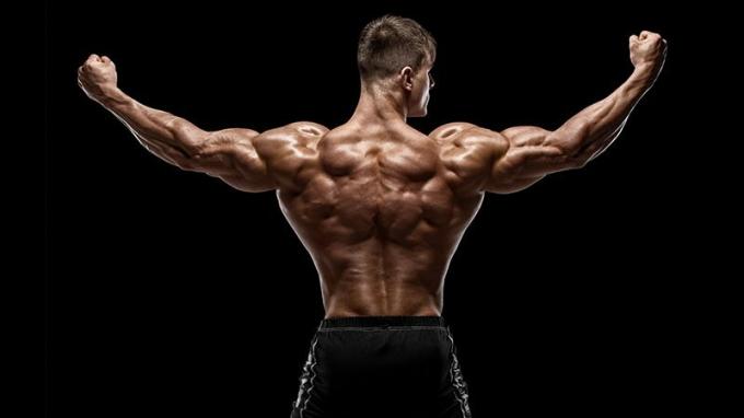 Lihaksikas mies näyttää selän lihaksia, eristetty mustalla taustalla.