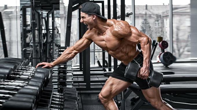 Muskulös man som tränar i gymmet gör övningar för ryggen. Enda