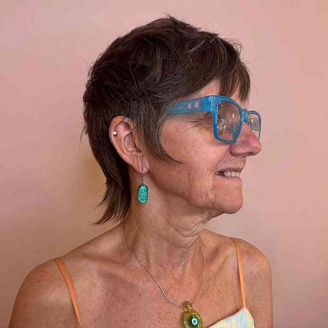 चश्मे के साथ 60 वर्ष से अधिक उम्र की वृद्ध महिलाओं के लिए ब्रुनेट मुलेट पिक्सी शेग बाल